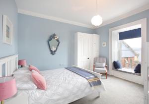 1 dormitorio con paredes azules y 1 cama con almohadas rosas en All Day View., en North Berwick