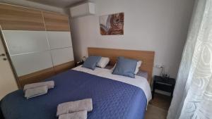 a bedroom with a blue bed with two towels on it at Apartman Z12 in Kornić