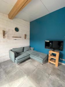 a living room with a couch and a flat screen tv at L'appartement de la Baie d'Authie in Fort-Mahon-Plage