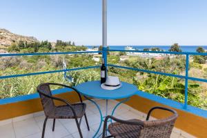 een blauwe tafel en 2 stoelen op een balkon met uitzicht op de oceaan bij Plastiras Sea View Apartments in Archangelos