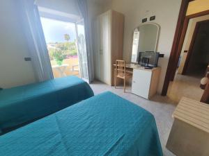 una camera da letto con due letti e una scrivania con televisione di Relais Villa agave a Ischia