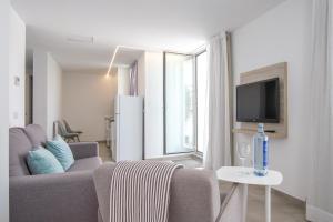 a living room with a couch and a tv at Sea Breeze Apartments in Cala Millor