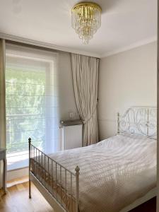 a bedroom with a bed and a chandelier and a window at Apartament Nadmorski Dwór- Gdańsk in Gdańsk