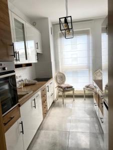 a kitchen with white cabinets and a large window at Apartament Nadmorski Dwór- Gdańsk in Gdańsk