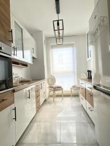 a kitchen with white cabinets and a large window at Apartament Nadmorski Dwór- Gdańsk in Gdańsk