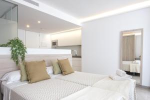 a white bedroom with a large white bed with pillows at Sea Breeze Apartments in Cala Millor