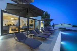 a row of lounge chairs with umbrellas and a pool at Villa Valdo by Istra Vacation in Marčana