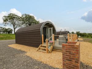 uma pequena cabana com um alpendre e uma parede de tijolos em Laird Lodge 2 em Lockerbie