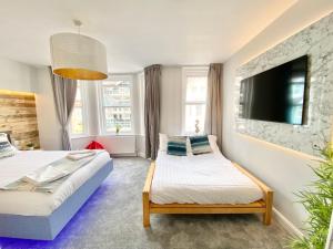 a bedroom with two beds and a flat screen tv at Coastline Retreats - Cloud9 Newly Renovated, Beautiful Ensuite Rooms Near Seafront in Town Centre, Netflix, SuperFast WiFi, Communal Kitchen in Bournemouth