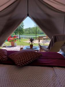 a bed in a tent with a view of a field at Aimasas Camping in Lielie Unguri