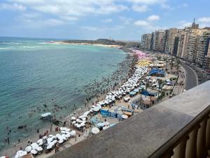 een druk strand met parasols en mensenmassa's bij شقق بانوراما شاطئ الأسكندرية كود 1 in Alexandrië