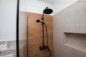 a shower in a bathroom with a wooden wall at Apartmani Barbaroša in Sveti Filip i Jakov