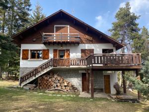 a house with a deck and a pile of logs at Chalet de l'Esquirol in Bolquere Pyrenees 2000