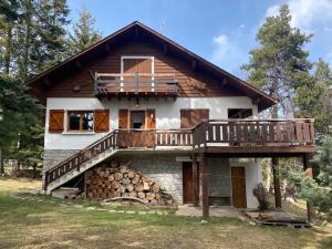 une maison avec une terrasse et un tas de bûches dans l'établissement Chalet de l'Esquirol, à Bolquère-Pyrénées 2000