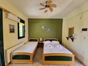 two beds in a room with a ceiling fan at Studios Achileous 1 in AgiaKampos