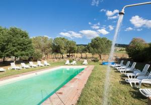 a swimming pool with chairs and a fountain at La Casa Di Campagna in Magione
