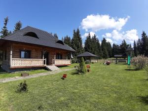 a log cabin in a field of green grass at Căsuța din Povești - Vatra in Vatra Dornei