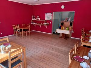 - une salle à manger avec des murs rouges, des tables et des chaises en bois dans l'établissement Pension am Filmpark, à Potsdam