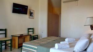 sypialnia z łóżkiem, stołem i telewizorem w obiekcie Porto Skala Village Hotel w mieście Skála Kefalonias