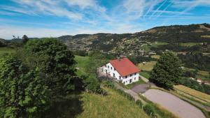 a white house with a red roof on a hill at Gîtes de Moyenmont in La Bresse