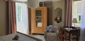 ein Schlafzimmer mit einem Schrank, einem Stuhl und einem Schreibtisch in der Unterkunft Le Gîte du Lapin Bleu in Baigneux-les-Juifs