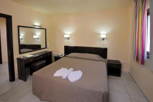 a bedroom with a bed and a dresser and a mirror at Nelia Gardens in Ayia Napa