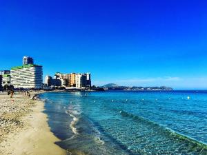 a beach with people swimming in the water and buildings at SERVICE APART LAZARO - Apartamentos Aguamarina 43-C in Calpe