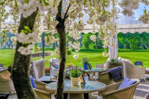 a patio with tables and chairs and trees with flowers at Formby Hall Golf Resort & Spa in Southport