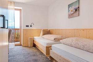 two beds in a room with a refrigerator at Living Lerchna - Apartment Abendrot in Maranza