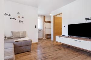 a living room with a flat screen tv and a couch at Living Lerchna - Apartment Abendrot in Maranza