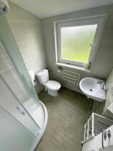 baño con aseo y lavabo y ventana en Jasmīni, en Ventspils