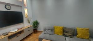 sala de estar con sofá gris y almohadas amarillas en Linda, en Tiflis