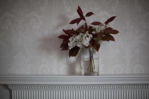 a vase filled with flowers sitting on a mantle at Trelough House B&B in Wormbridge