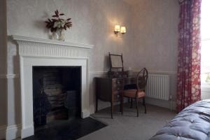 a bedroom with a fireplace with a desk and a chair at Trelough House B&B in Wormbridge