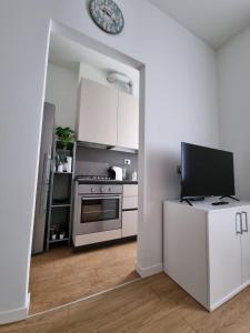 eine weiße Küche mit einem Herd und einem TV in der Unterkunft Claro Apartments - Prampolini 12 in Mailand
