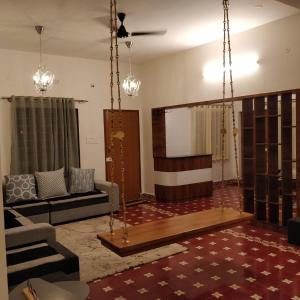 uma sala de estar com um sofá e um baloiço em NanDha Illam- The Courtyard Heritage HomeStay em Yelagiri