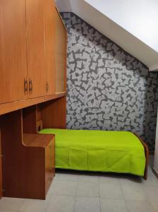 a bedroom with a green bed and a stone wall at La Rosa Dei Venti in Castellammare del Golfo