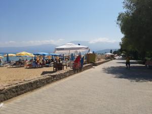 a beach with umbrellas and people sitting on the sand at Elio's Holiday Home in Pogradec