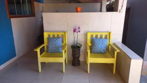 Dos sillas amarillas y un jarrón con flores. en Casa Esmeralda para descanso, en Pirenópolis
