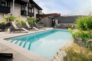 a swimming pool in a yard with chairs and a house at Hotel Park Cafe Reichl in Bad Abbach