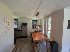 a dining room with a table and a kitchen at sfeervol vrijstaand huisje 6 persoons ruime tuin, centraal bij Nijmegen in Ewijk