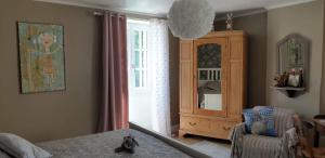a bedroom with a cabinet and a chair and a window at Le Gîte du Lapin Bleu in Baigneux-les-Juifs