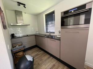 a large kitchen with a sink and a microwave at sfeervol vrijstaand huisje 6 persoons ruime tuin, centraal bij Nijmegen in Ewijk +18 photos