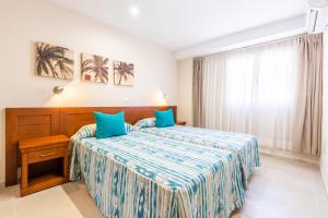 a hotel room with a bed with blue pillows at Apartamentos Vista Sur in Playa de las Americas