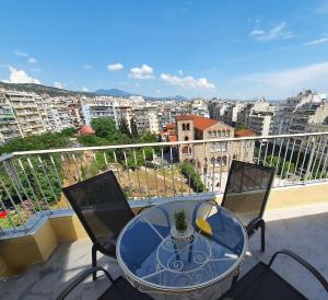 a glass table and chairs on a balcony with a view at nona's in Thessaloniki