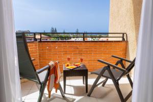 un balcón con 2 sillas y una mesa con fruta. en MUR Neptuno Gran Canaria - Adults Only, en Playa del Inglés