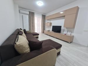 uma sala de estar com um sofá castanho e uma televisão em Apartament Moghioros Park Residence DUM1 em Bucareste