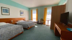 a hotel room with two beds and a flat screen tv at Elekt Czaplinek in Czaplinek