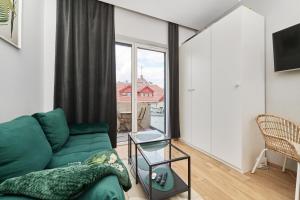 een woonkamer met een groene bank en een raam bij Apartment By the Oder River Wrocław by Renters in Wrocław