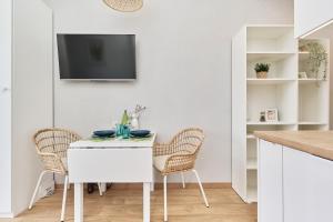 a white kitchen with a white table and chairs at Apartment By the Oder River Wrocław by Renters in Wrocław